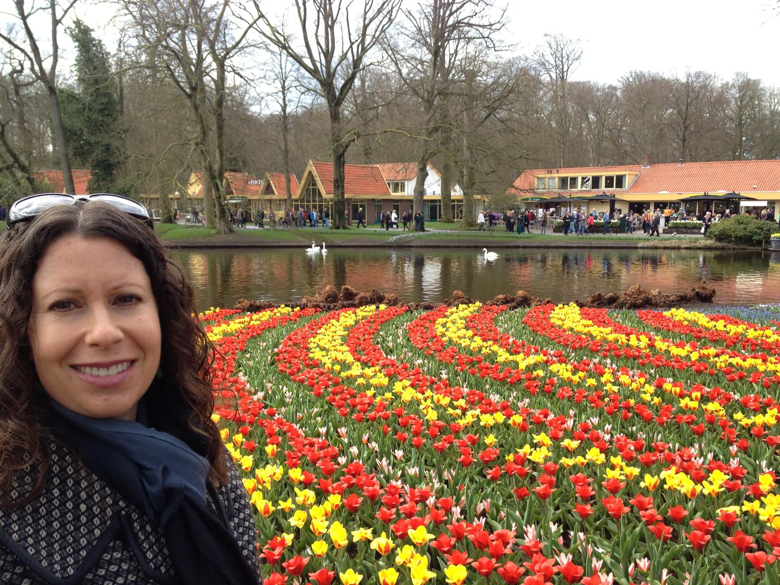 Author Liz Humphreys smiling next to tulip field in Amsterdam