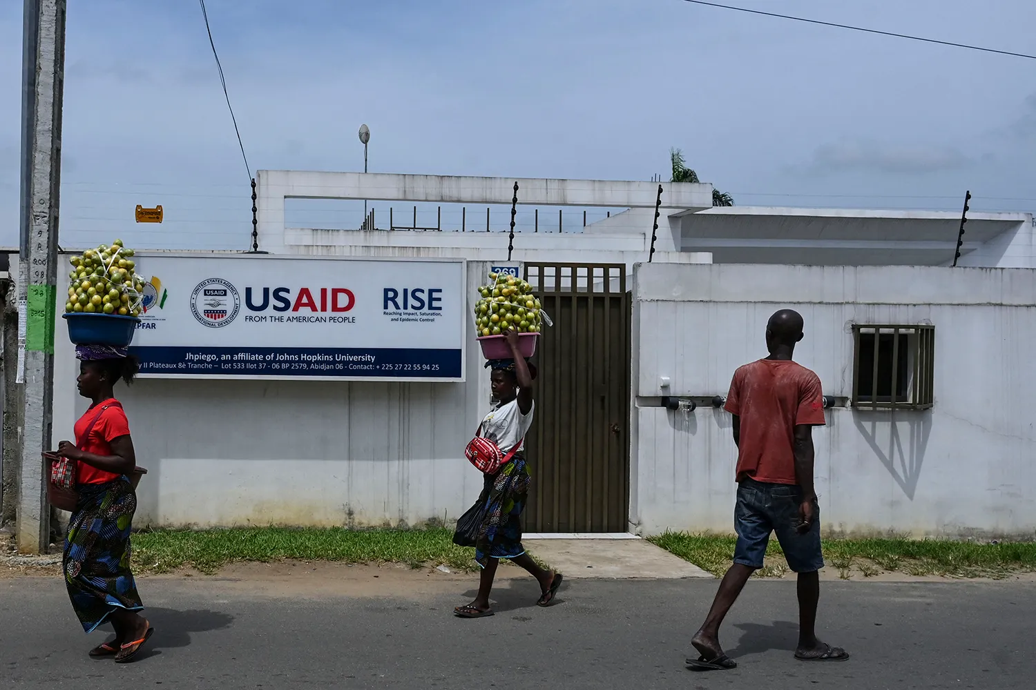 Street vendors walk past a USAID office in Africa.