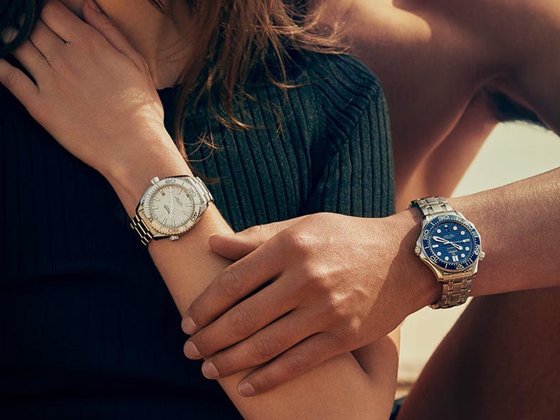 A woman and man wearing Omega Seamaster watches