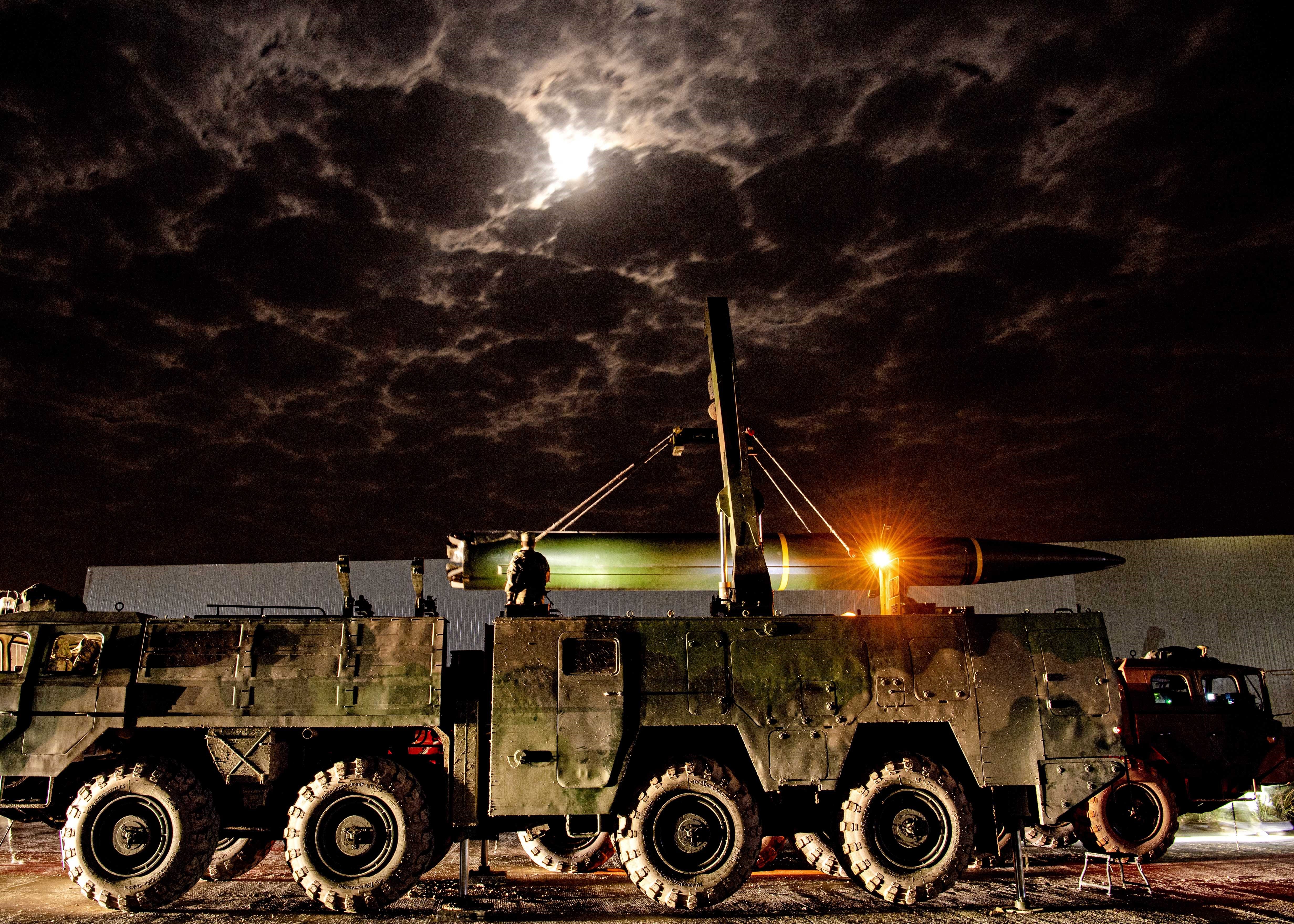 A Chinese missile sits on a military truck on a road at night.