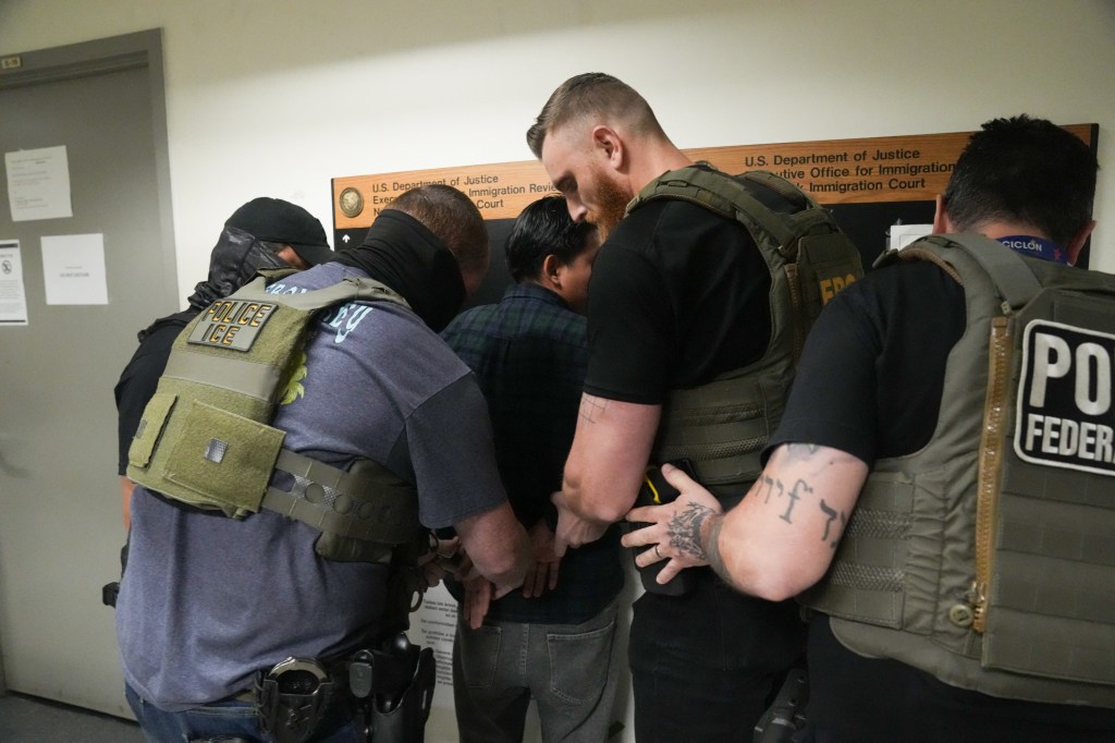 ICE agents arresting an immigrant in a courthouse.