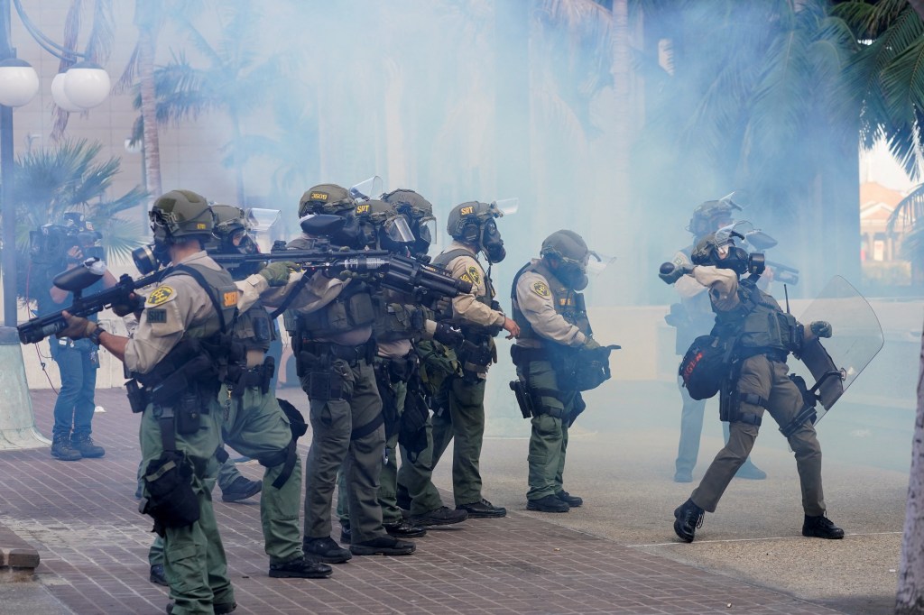 LA Sheriff deputies react amid tear gas as people protest in Los Angeles.