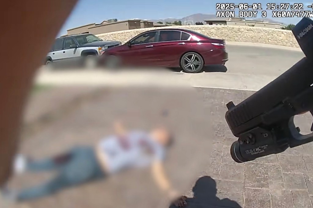 Body camera footage of a person lying on the ground, blurred for privacy, near a red car and a white SUV.