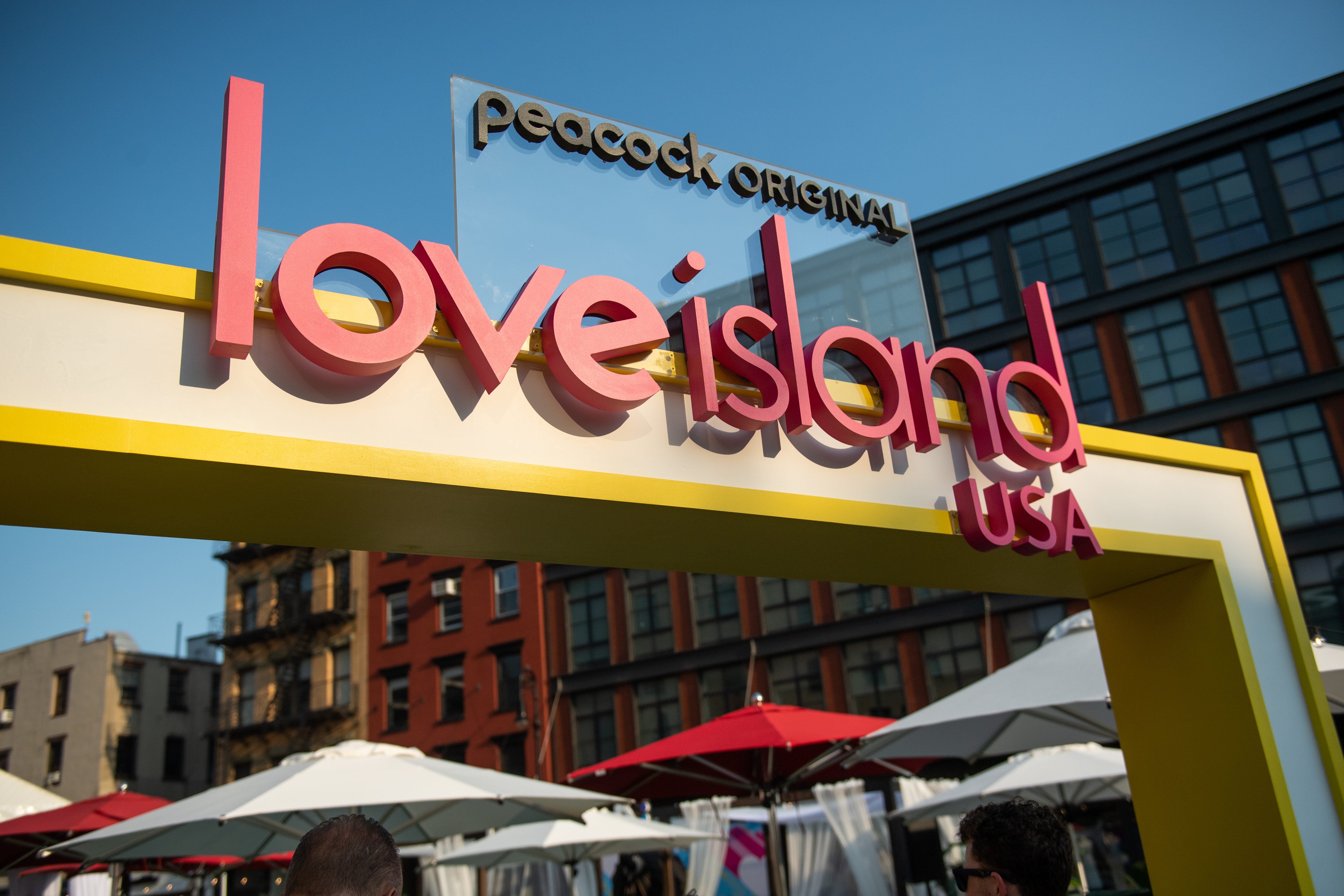The "Love Island USA" logo is under a "Peacock Original" sign displayed outdoors.