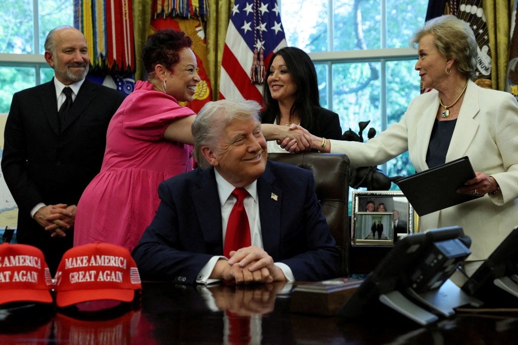 President Donald Trump sits in the Oval Office of the White House as Secretary of Education Linda McMahon shakes hands with Annette Albright on April 23, 2025.