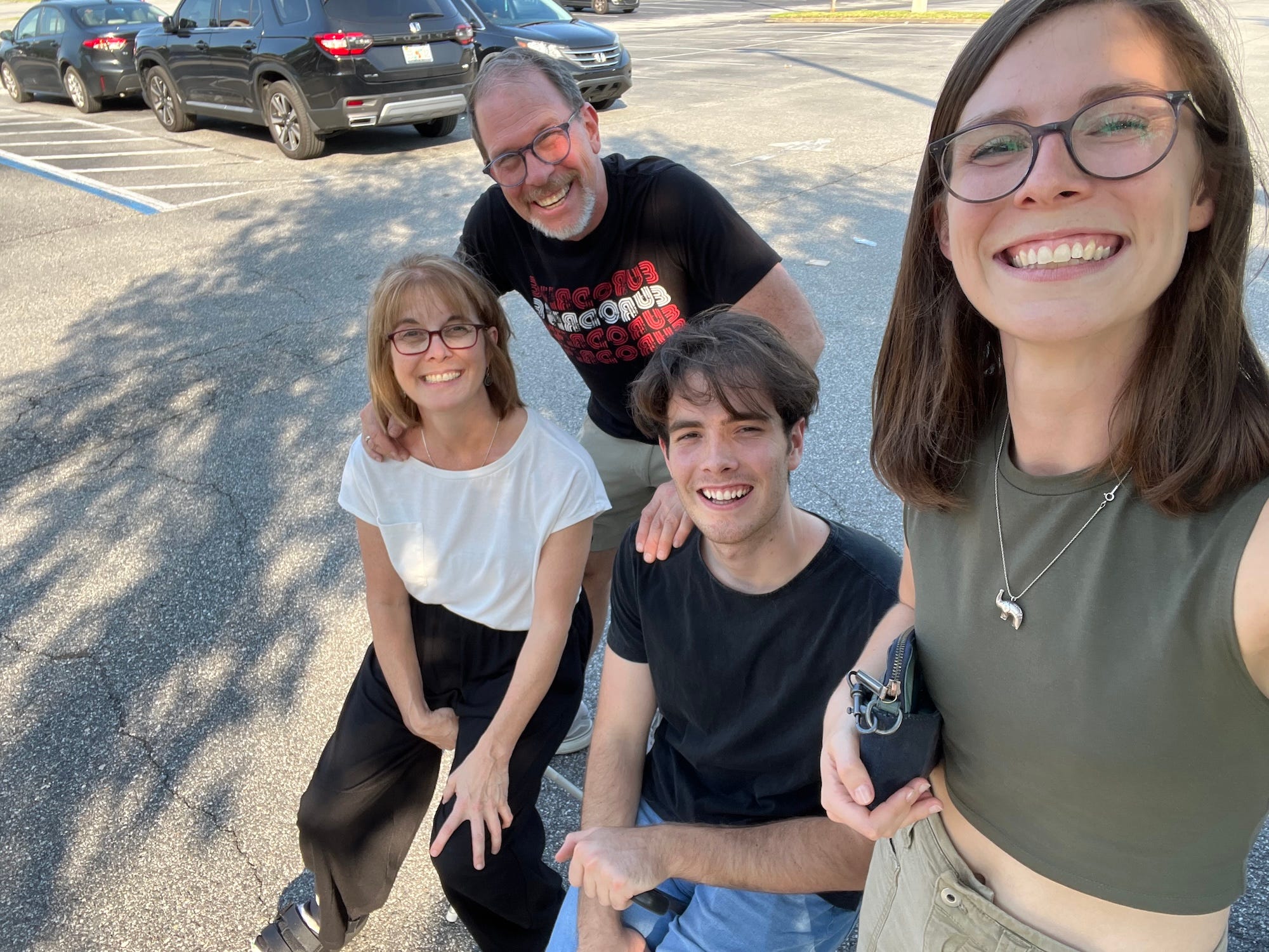 A selfie of a family of four in a parking lot.