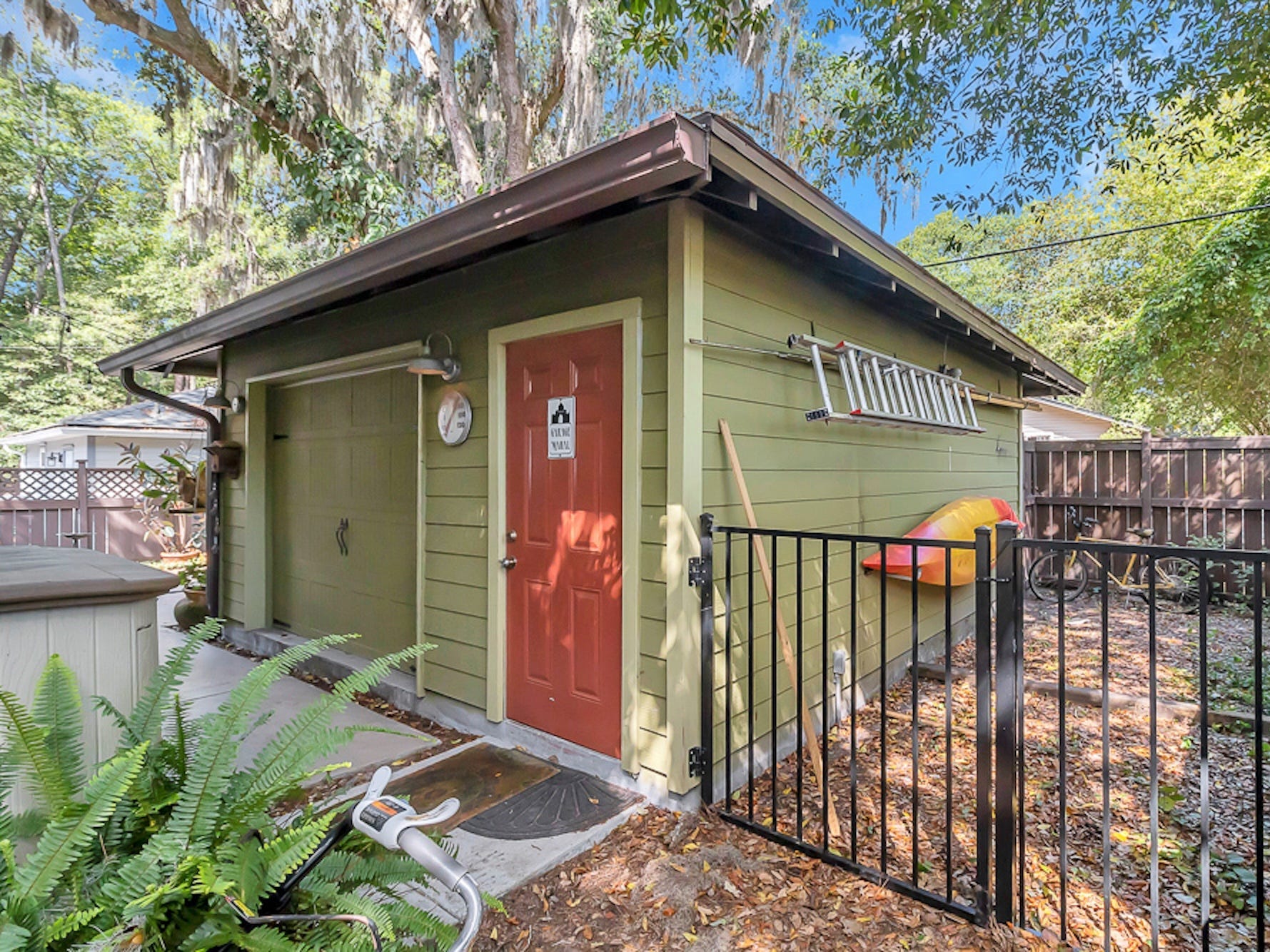 A green garage apartment in a backyard.