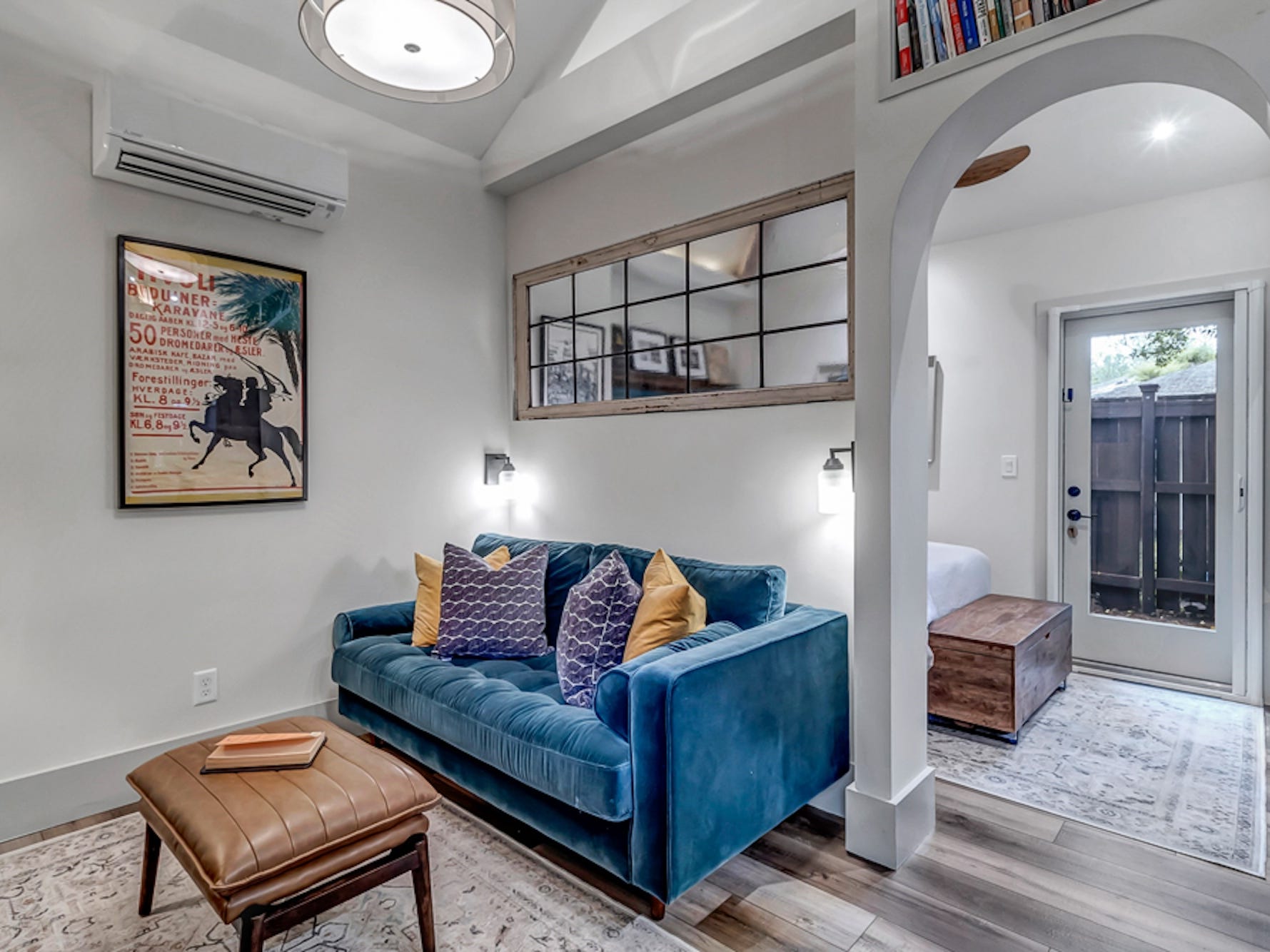 A photo of a small living area with an archway leading to a bedroom.