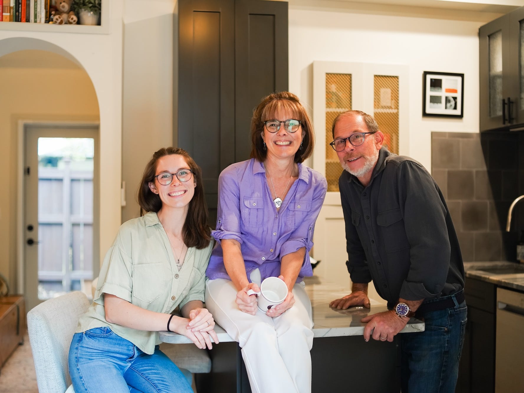 Three people gathered at a countertop in a kitchen.