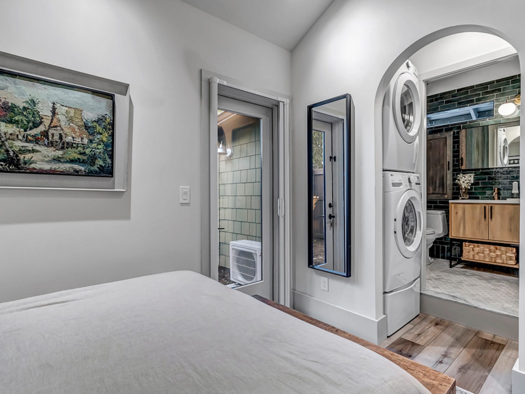 A bedroom with an entryway leading to a bathroom with laundry stacked atop it.