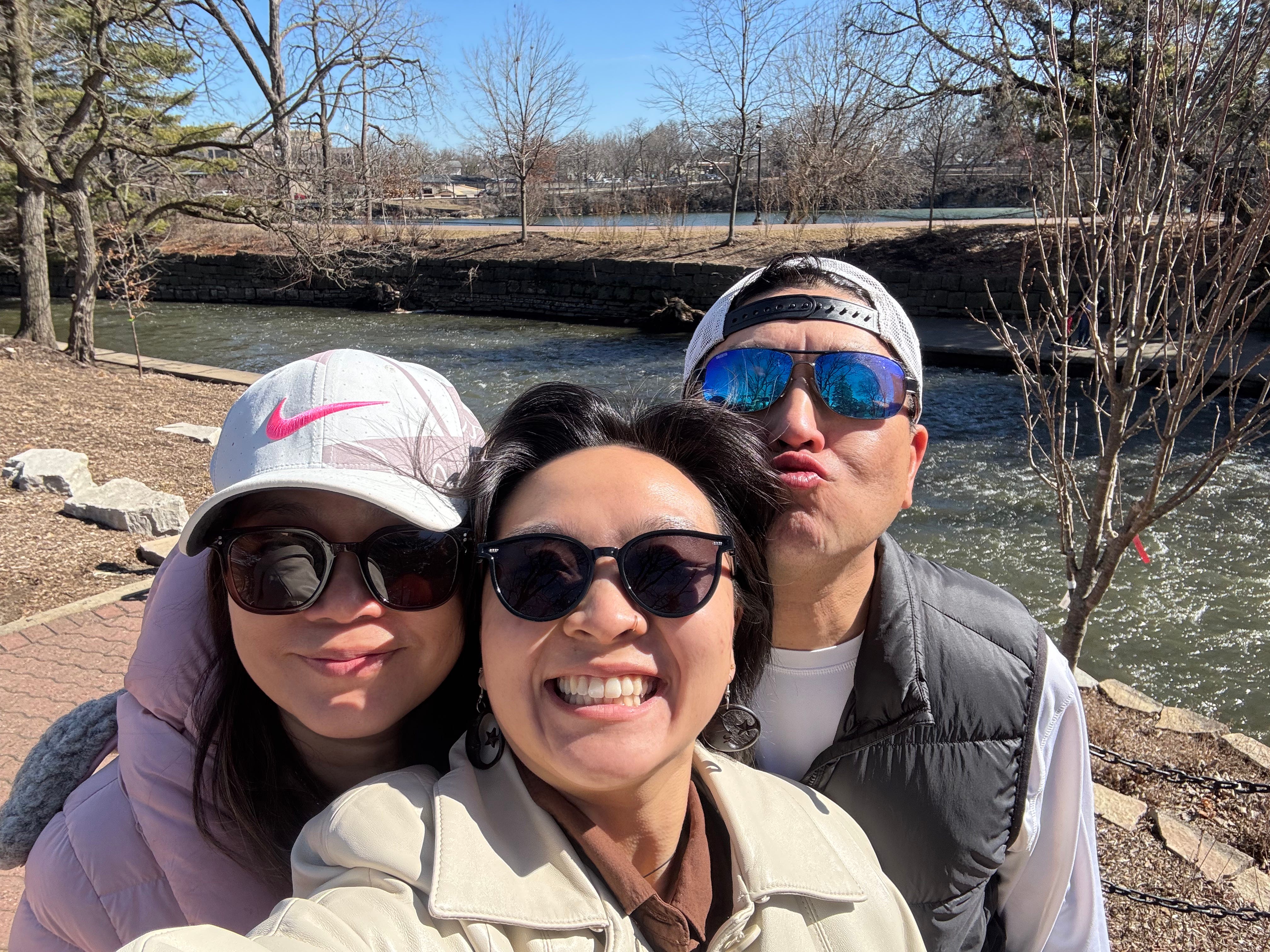 Christina poses with her parents in a park.