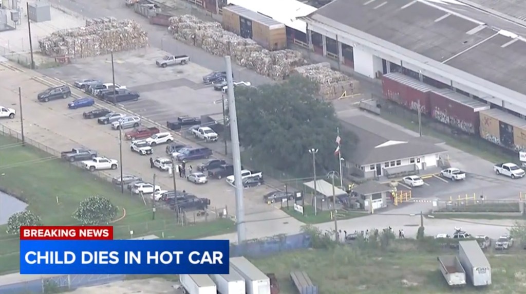 Aerial view of a factory parking lot with emergency vehicles; child dies in hot car.