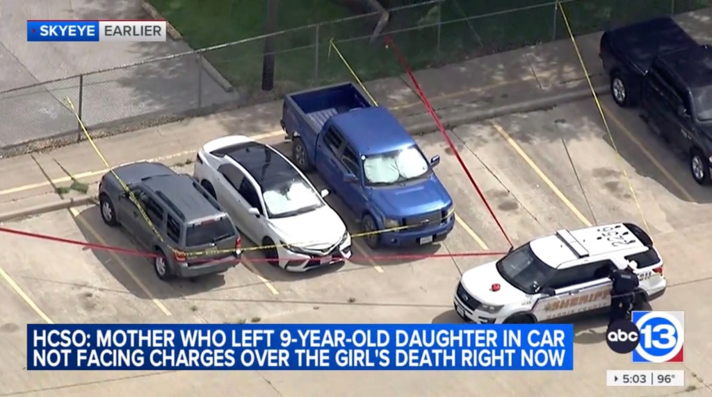 Aerial view of a parking lot with police tape around three cars, one of which is a police vehicle.