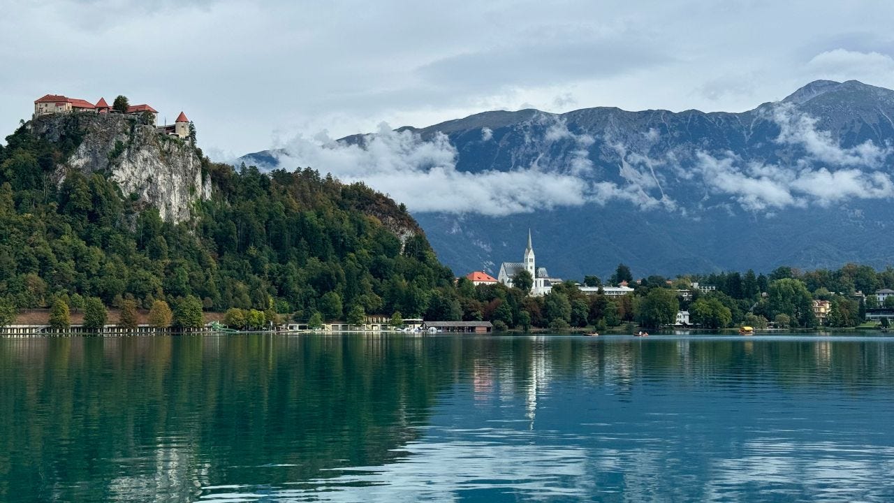Water of Lake Bled reflecting buildings, trees surrounding it 