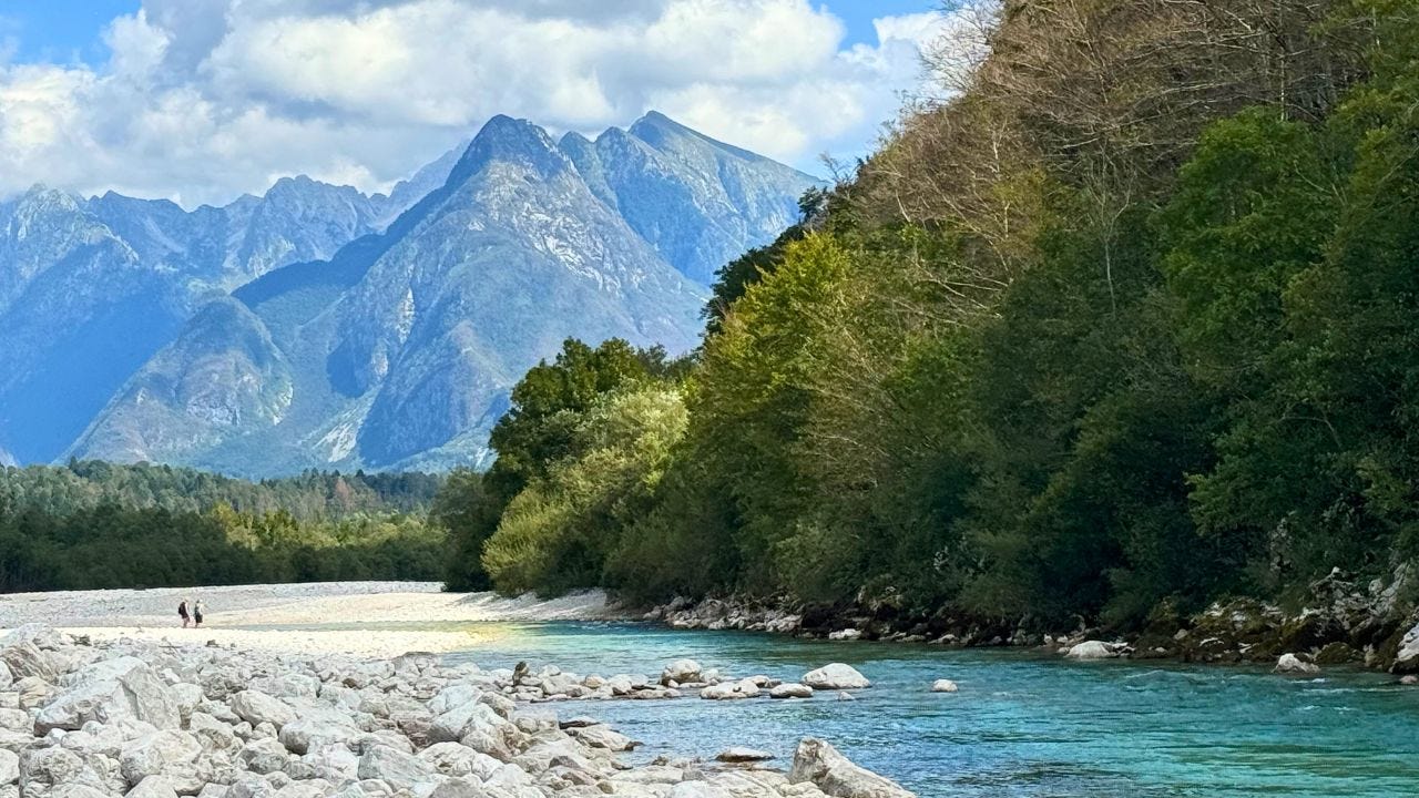 View of Soca River with green and blue mountains behind it 