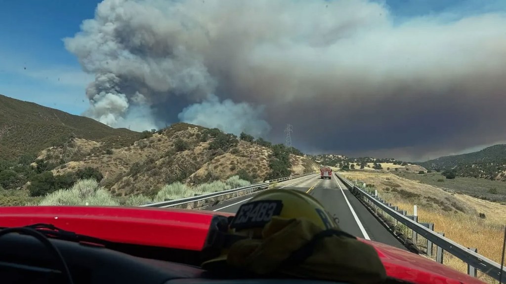 Large wildfire smoke plume seen from a highway.