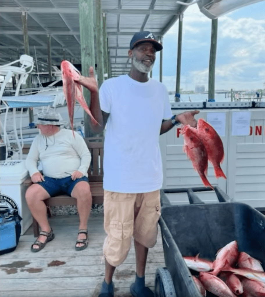 Man holding several red snapper fish.