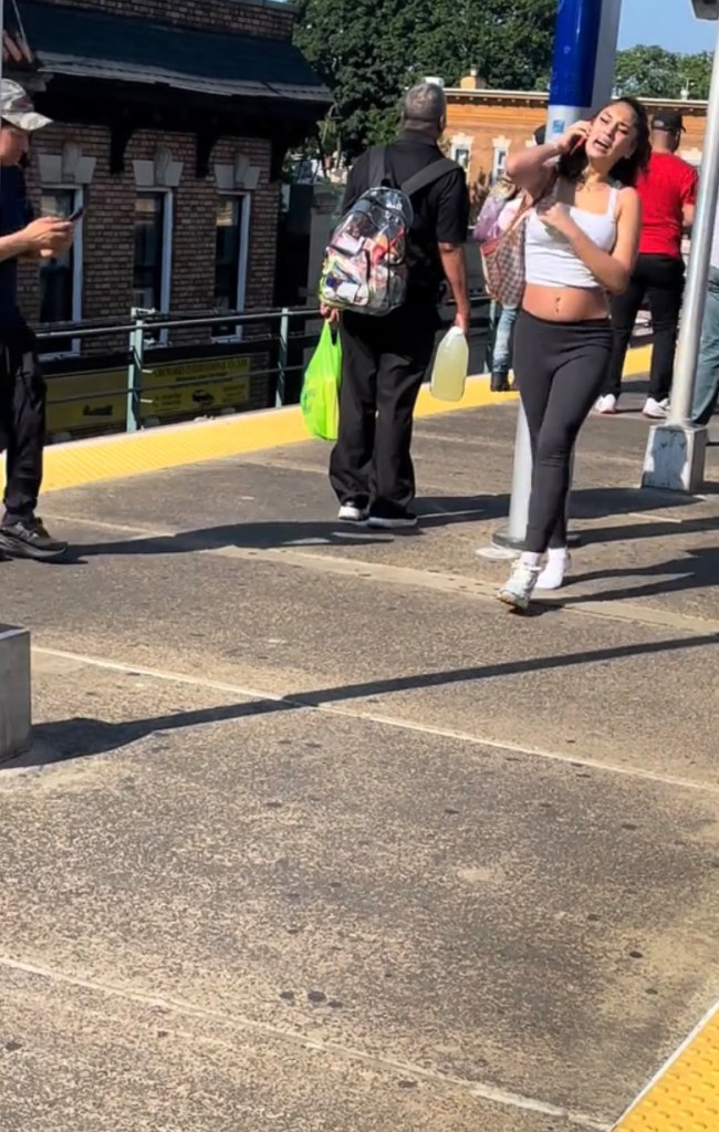 A woman on a subway platform talking on her phone.
