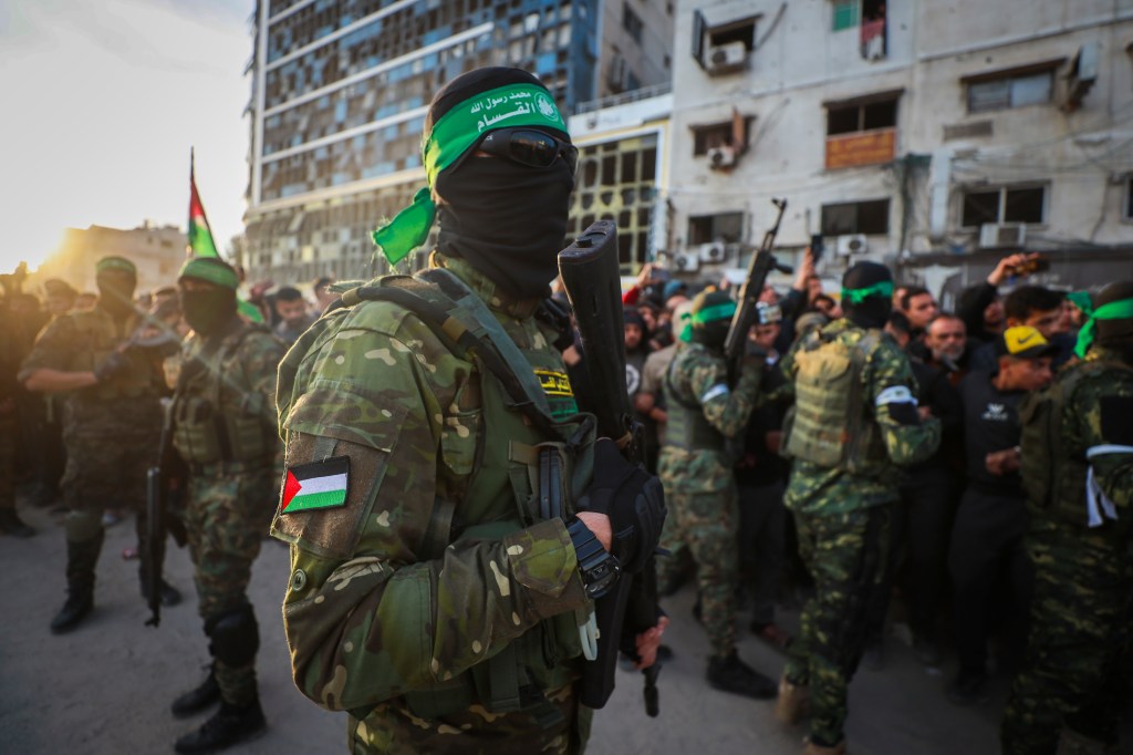 Fighters from the Qassam Brigades, the military wing of Hamas, control the crowd as Red Cross vehicles manoeuvre to collect Israeli hostages to be released under a ceasefire agreement between Israel and Hamas, in Gaza City, Sunday, Jan. 19, 2025.