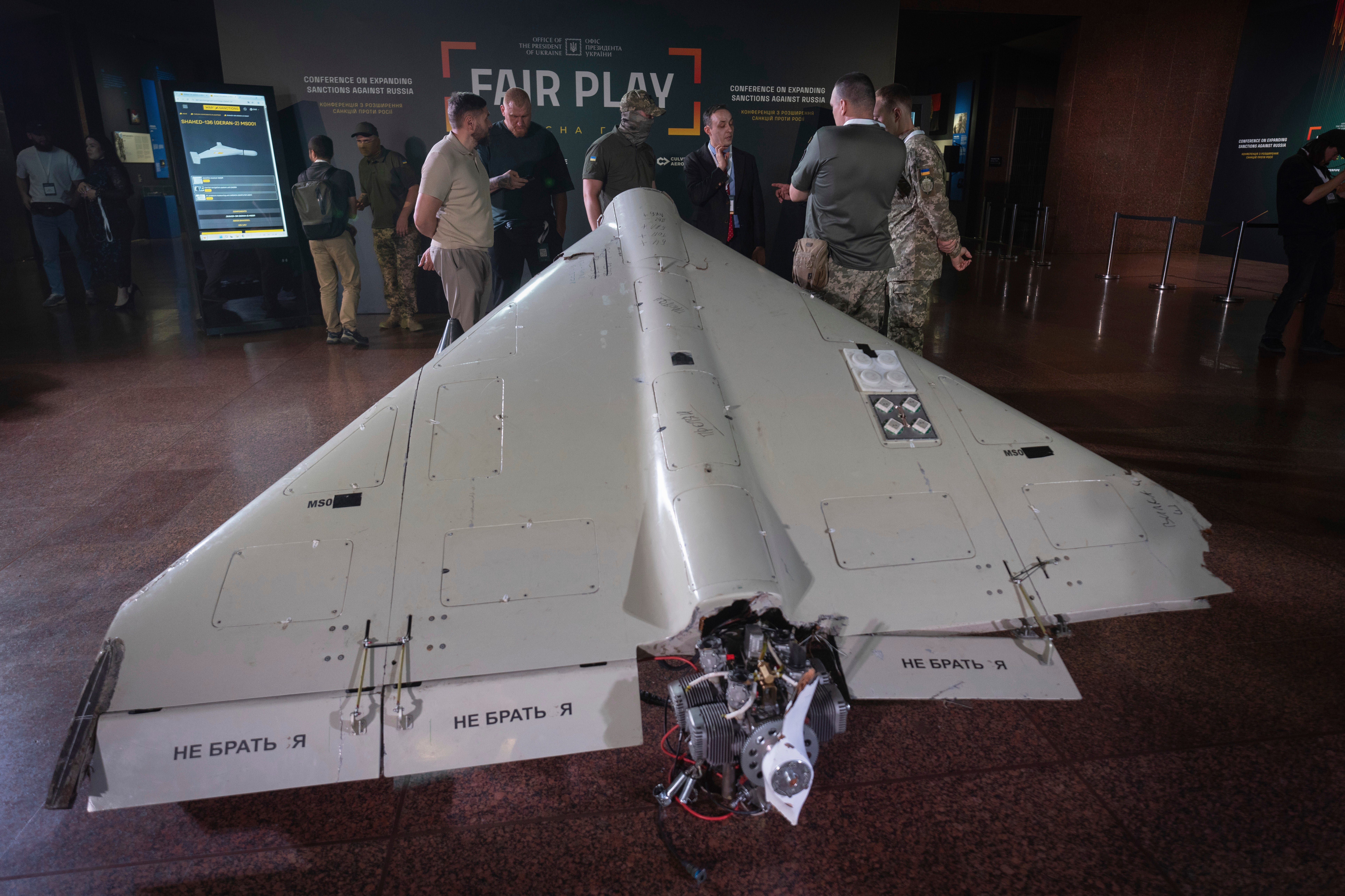 Visitors look at a damaged Iranian-made Shahed drone during the International Conference on Expanding Sanctions Against Russia in Kyiv, Ukraine, Friday, June 27, 2025.