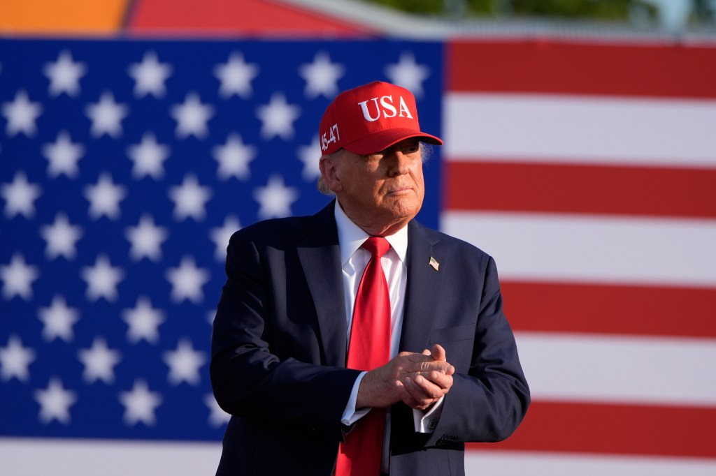 Donald Trump at a rally in front of a US flag.