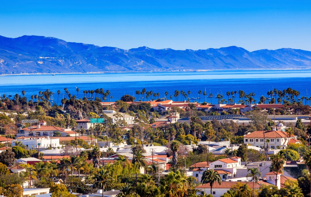 Santa Barbara, California coastline with ocean, mountains, and city buildings.