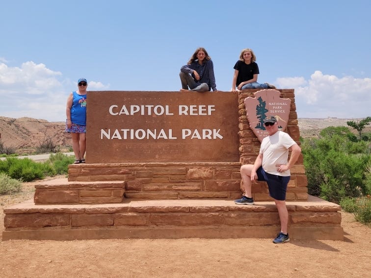 The Kosters sitting and standing around the Capitol Reef National Park sign.