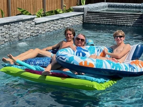 Three men in a pool with floaties.