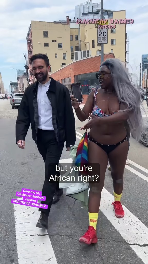 A man and woman on a city street; the man is asking the woman if she is African.