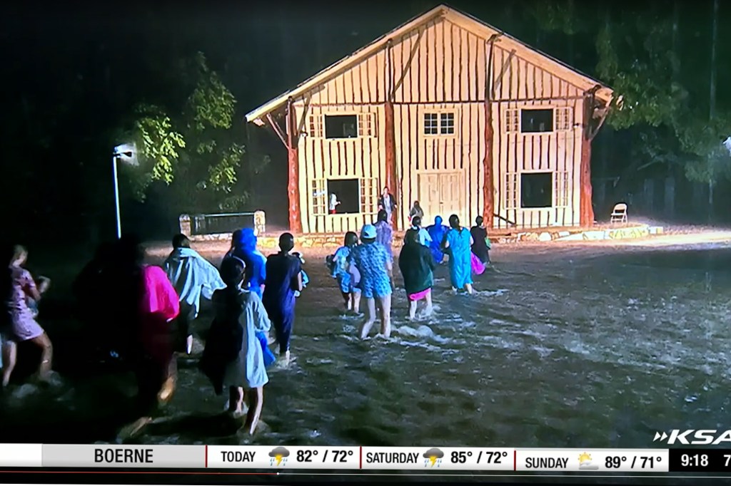 Campers wading through floodwaters at night.