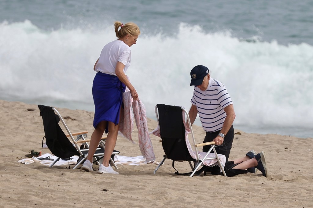 Joe Biden and a woman on Malibu beach; he is kneeling after falling from a beach chair.