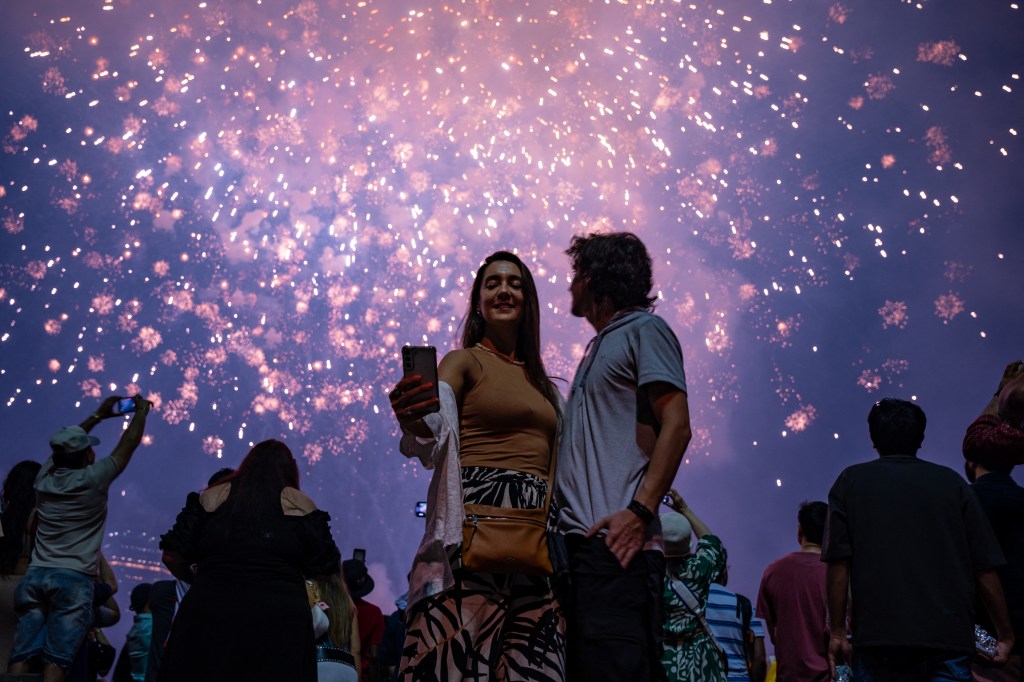 Couple taking a selfie with fireworks display in background.