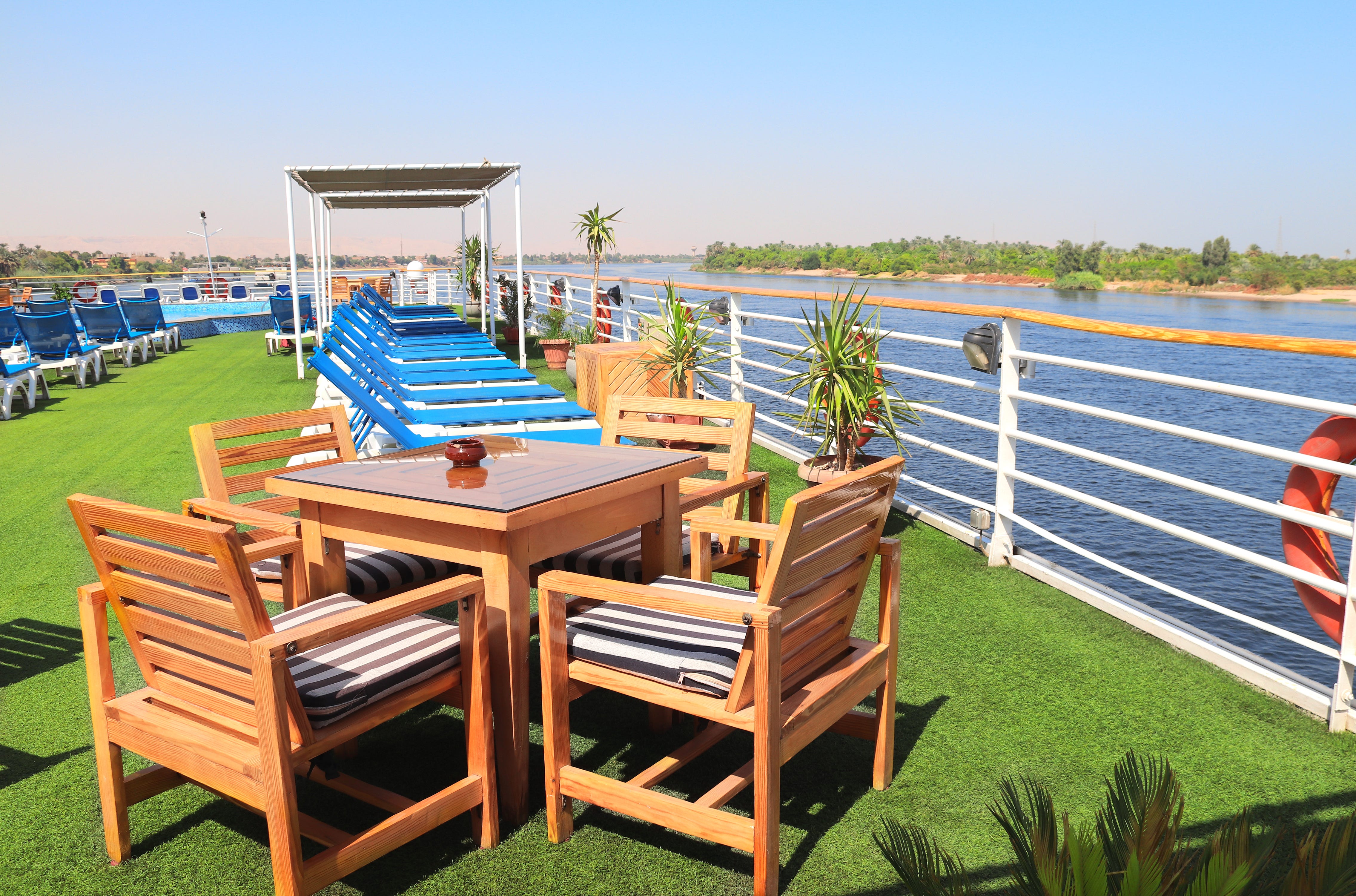 Empty tables and chairs on a turf-covered deck on a ship