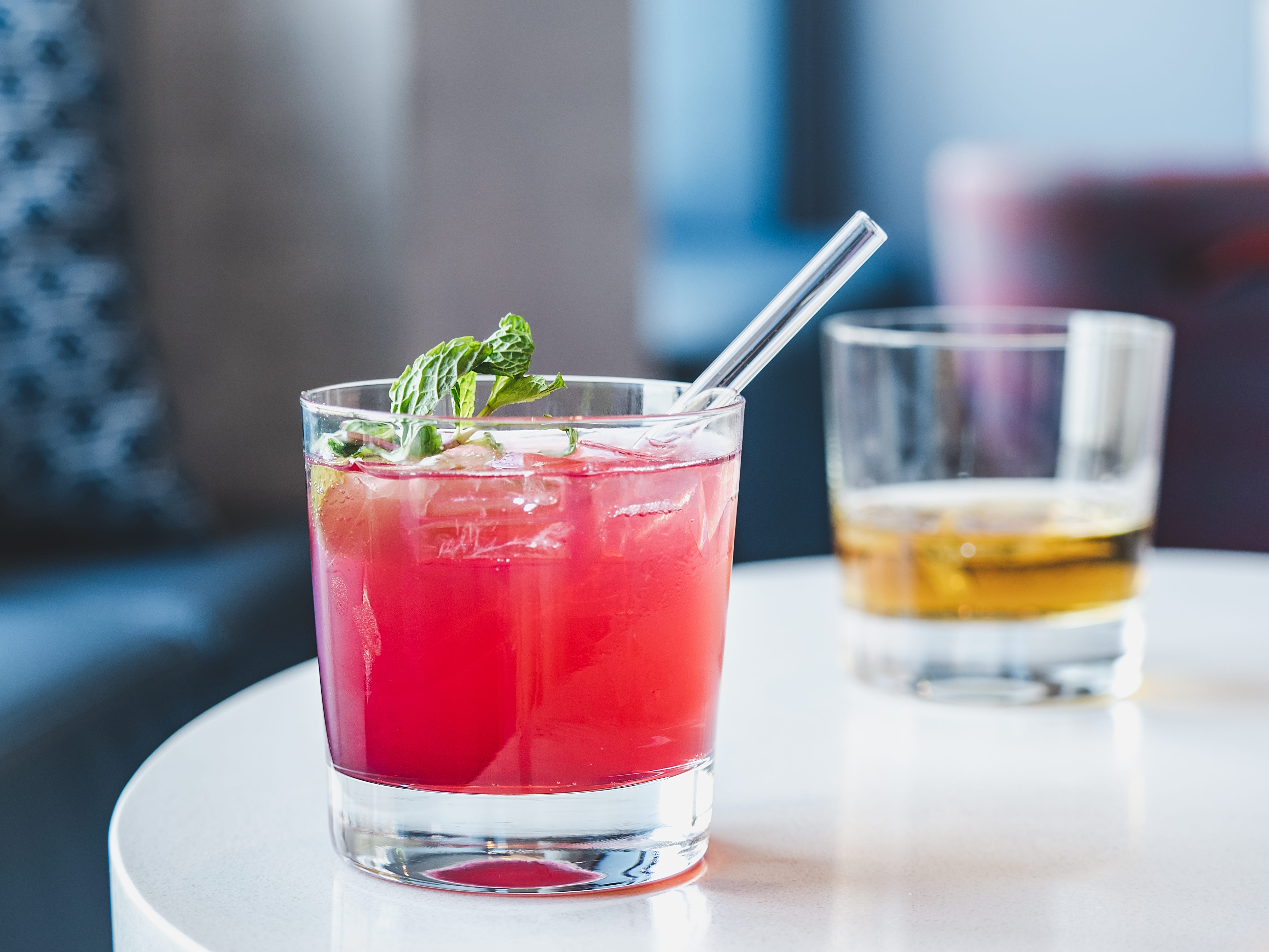 Cocktail on a round white table with another behind it