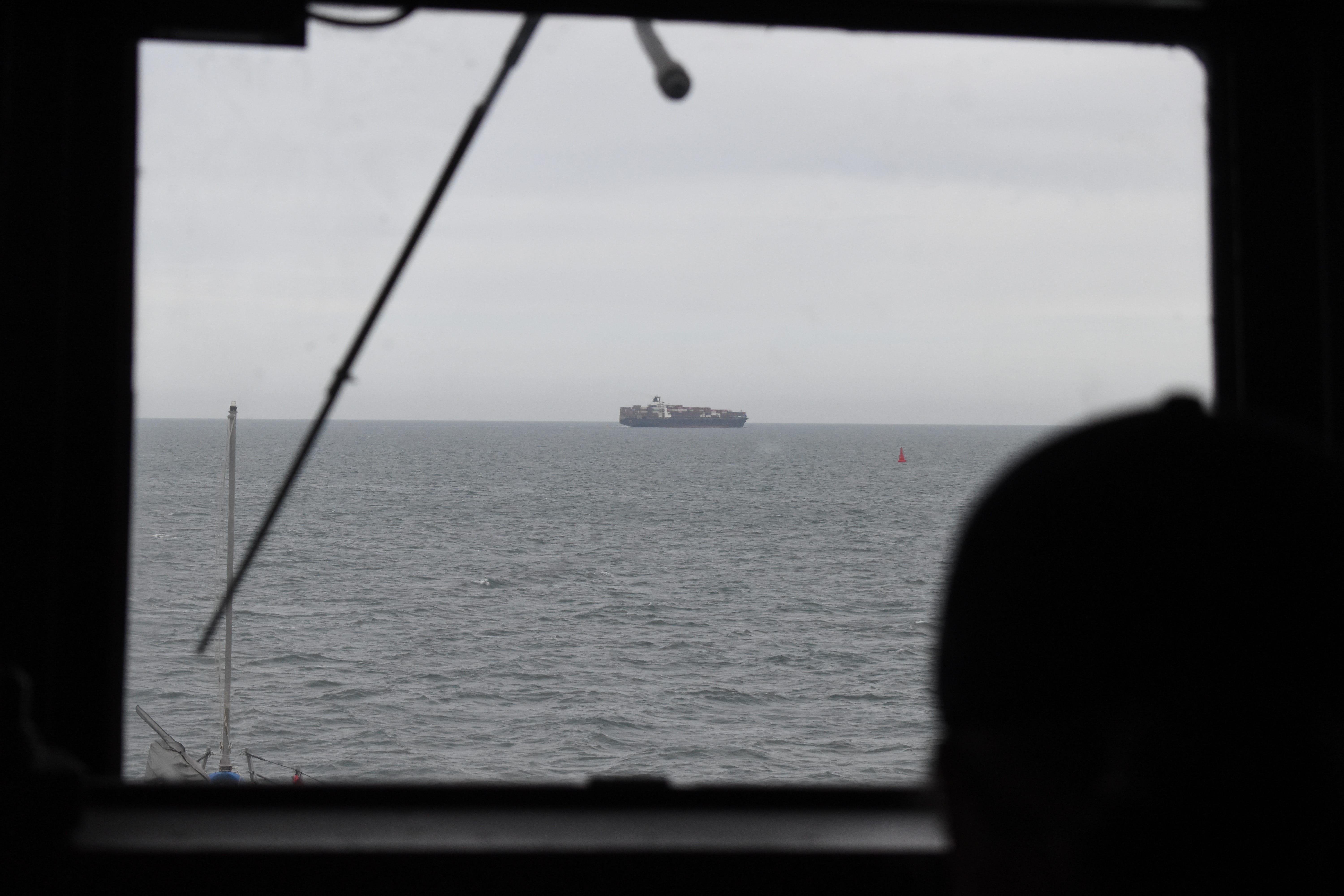 Sailors on the Navy destroyer USS Thomas Hudner watch a cargo ship in the distance in May 2025.