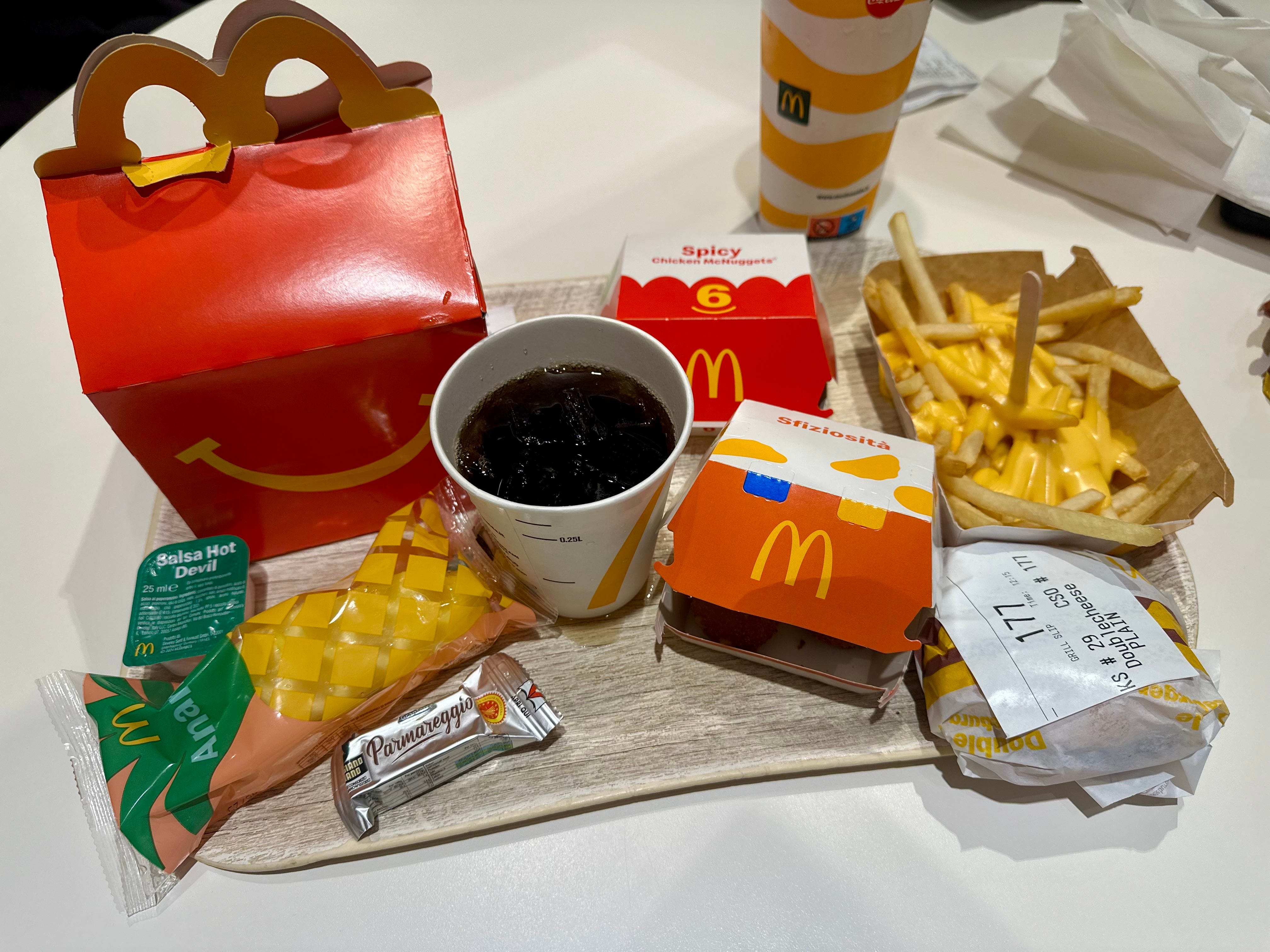 A tray at McDonald's in Italy with fries, sandwiches, a soft drink and other food items.