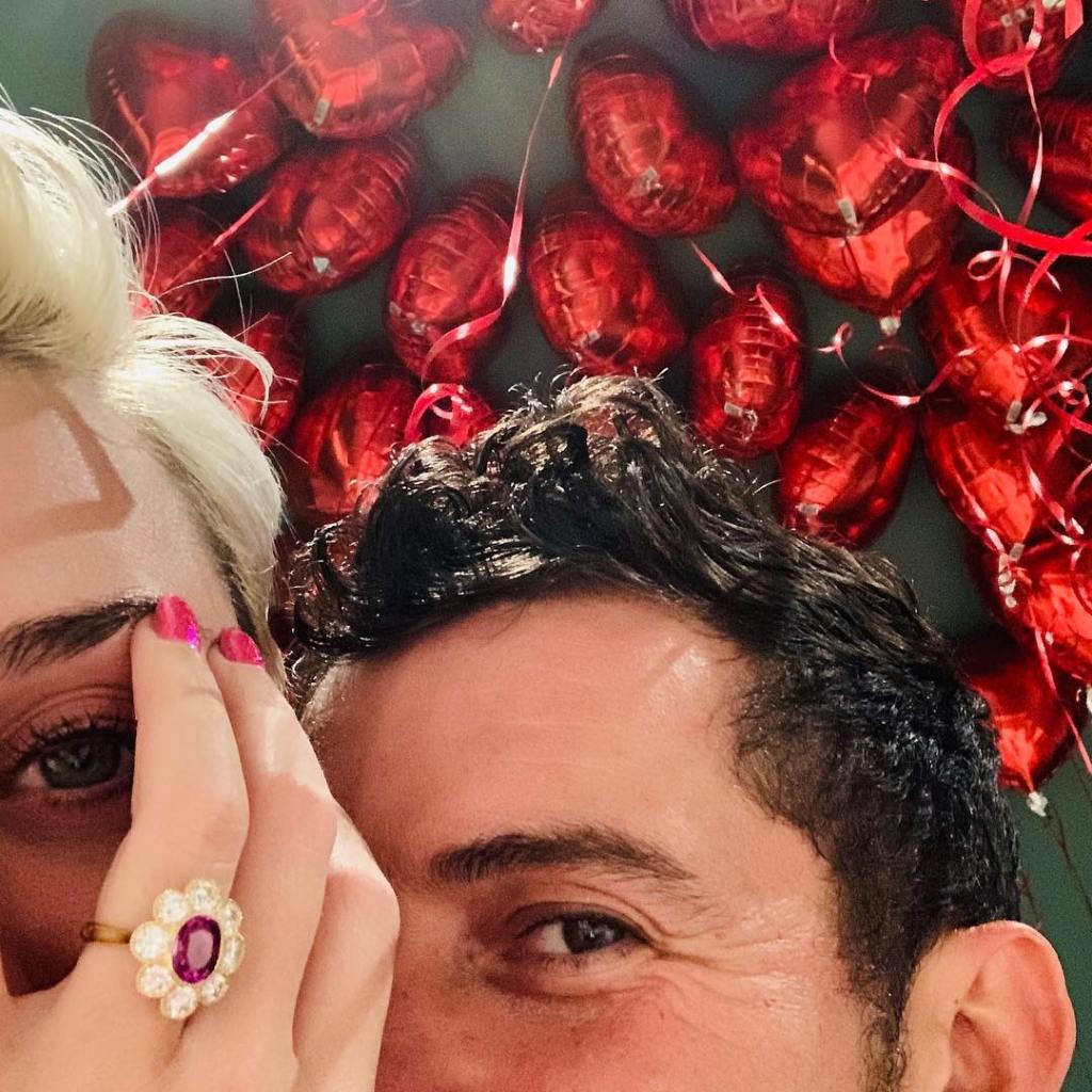 Katy Perry flaunting her daisy-shaped diamond engagement ring from Orlando Bloom with Bloom pictured next to her.