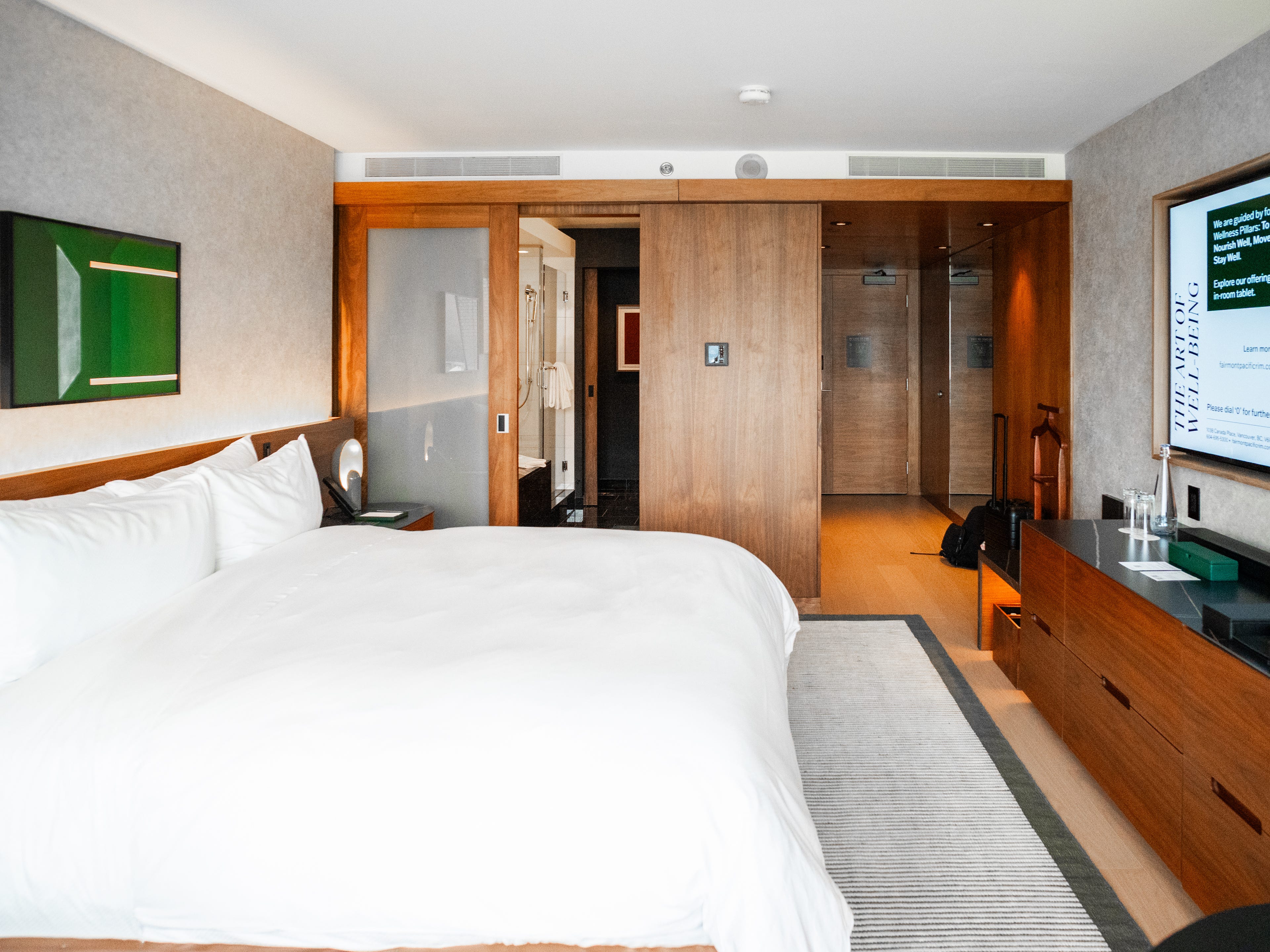 Inside a Fairmont Gold hotel room with a bed on the left, a TV on the right, and a bathroom in the back