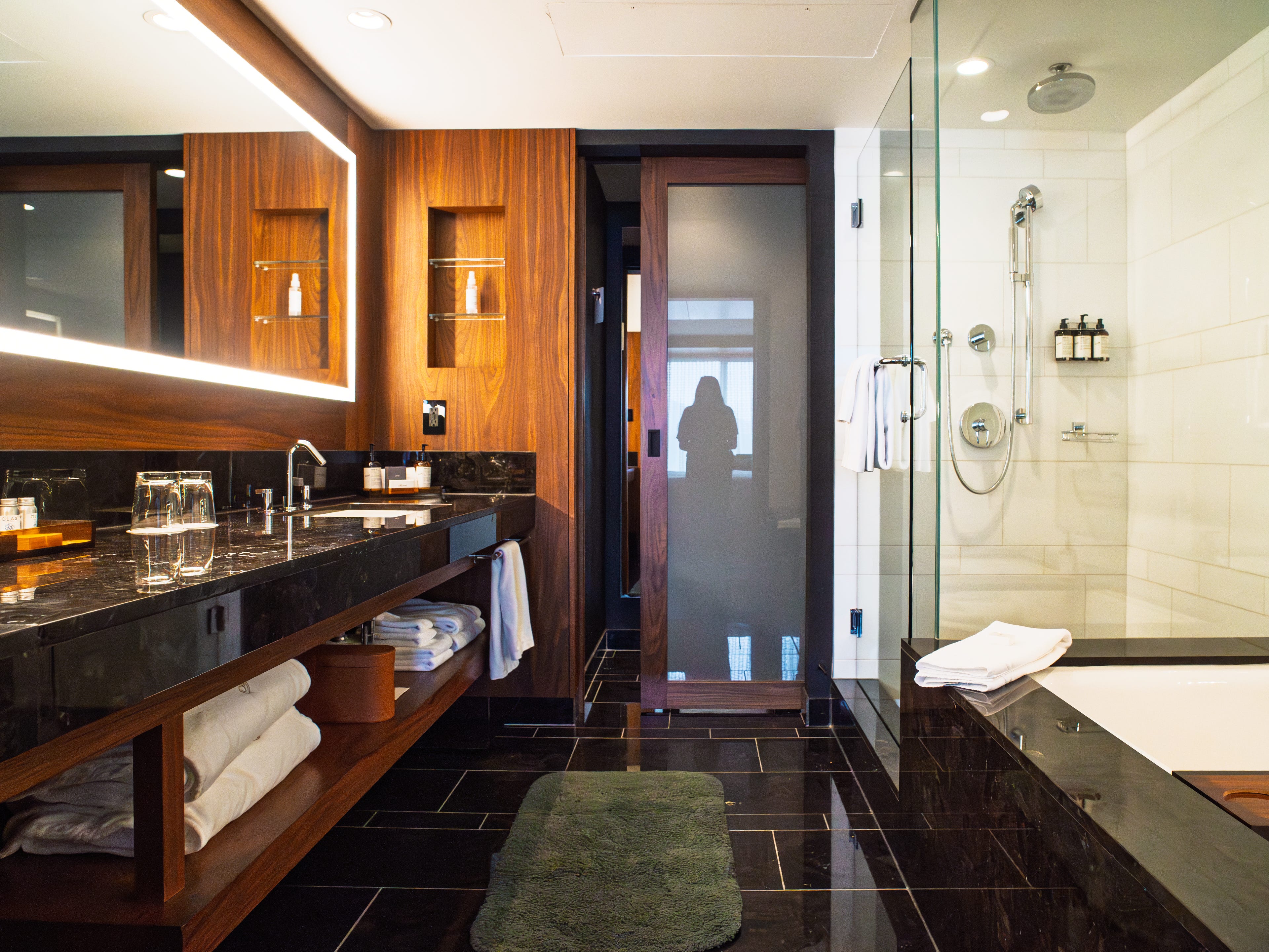 Inside a Fairmont Gold hotel room bathroom with black marble tiles, a tub and shower on the right and a double sink and vanity on the left