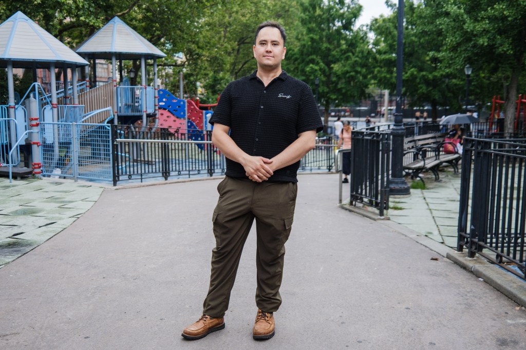 A man stands in front of a playground.