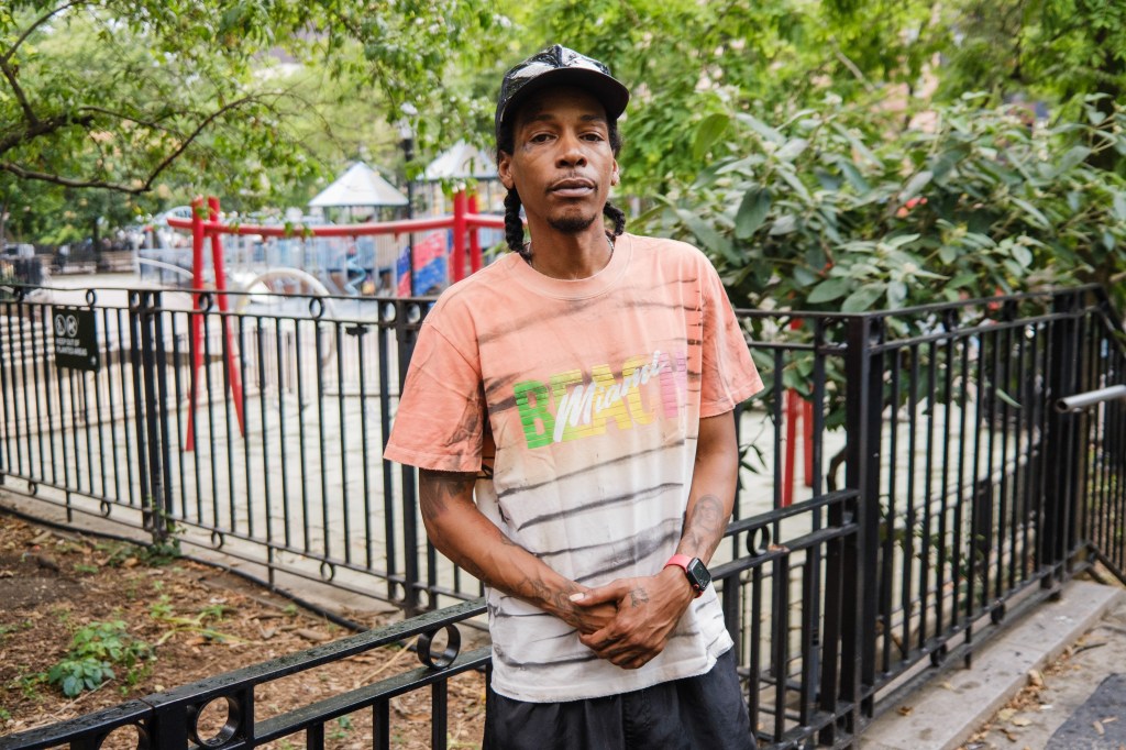 Man standing in a park near a playground.