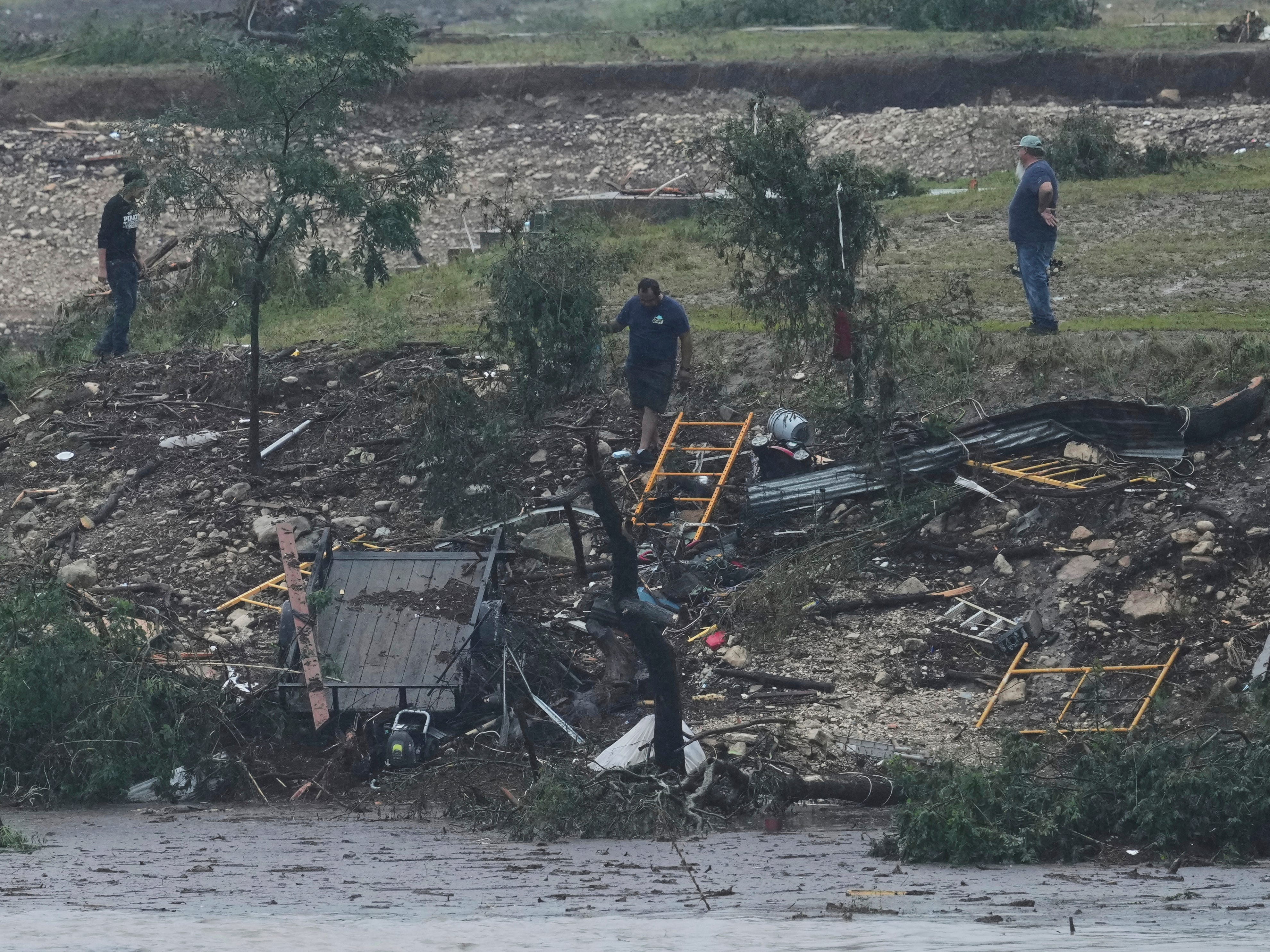 Men survey damage left by a raging Guadalupe River, Friday, July 4, 2025, in Kerrville, Texas.