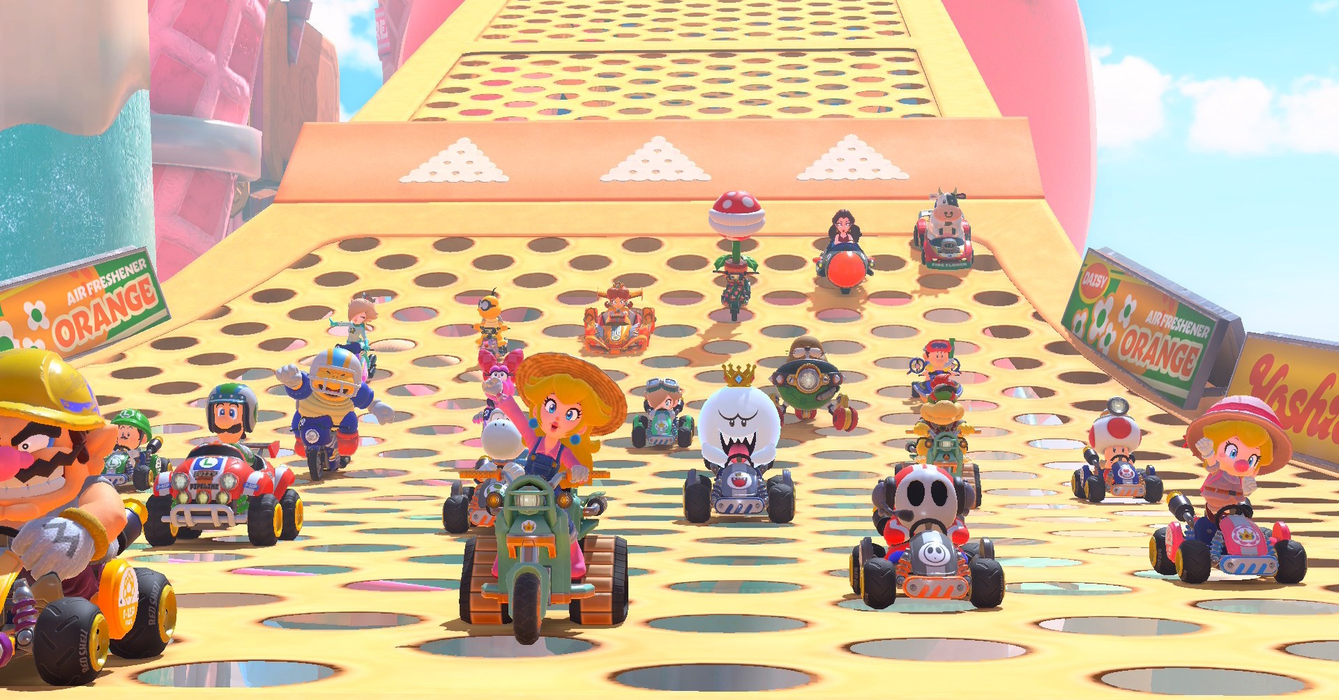 A full set of 24 racers in Mario Kart World, with Peach and Wario in the lead