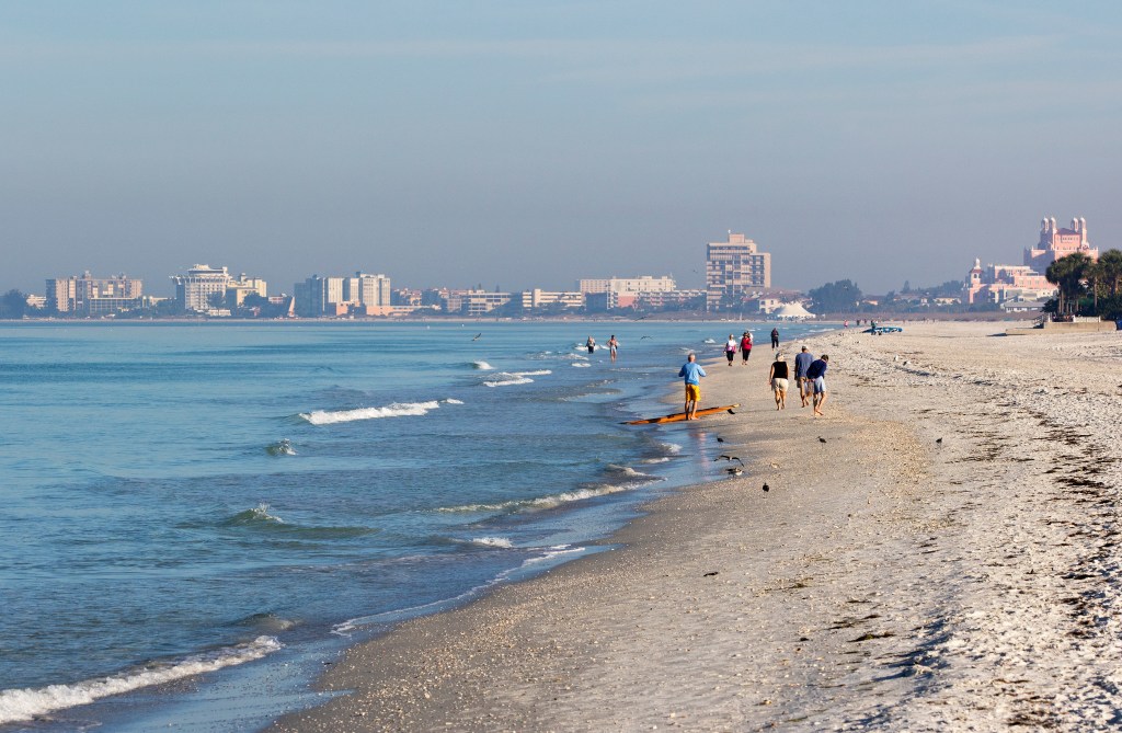 People walking along a beach in St. Pete Beach, Florida.