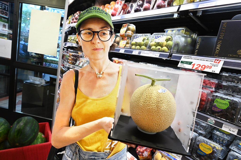 Woman holding a $130 Japanese melon in a grocery store.