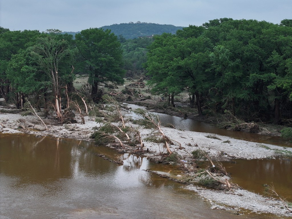 Drone view of flash flooding in Ingram, Texas, showing downed trees and debris in the Guadalupe River.