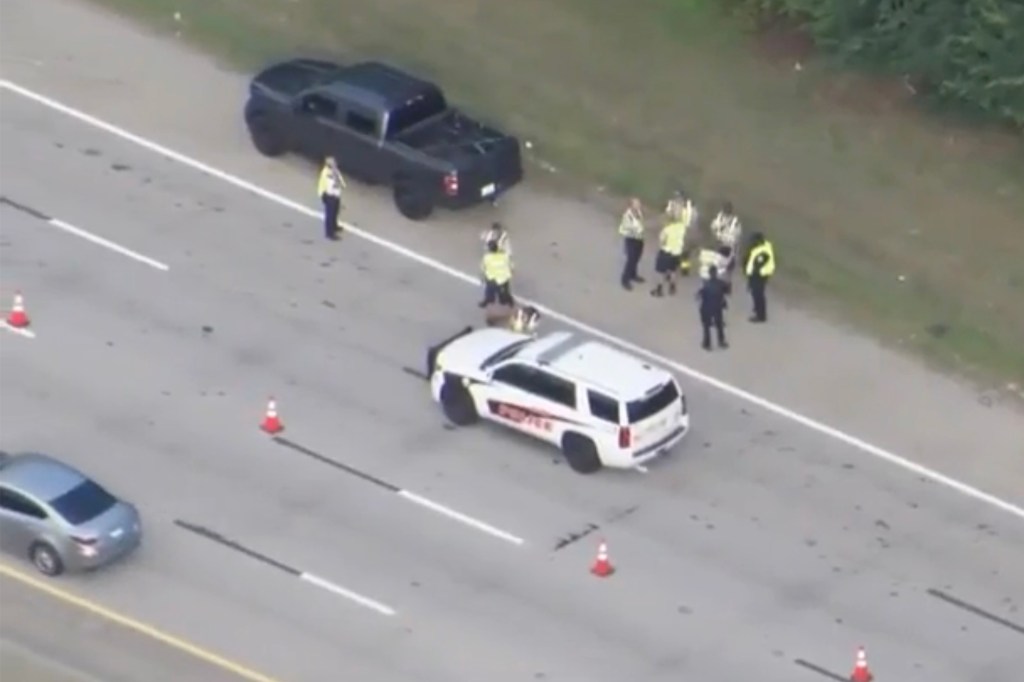 Aerial view of a highway incident scene with police officers, vehicles, and traffic cones.
