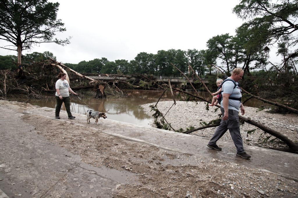 Family walking past flood damage in Kerrville, Texas.