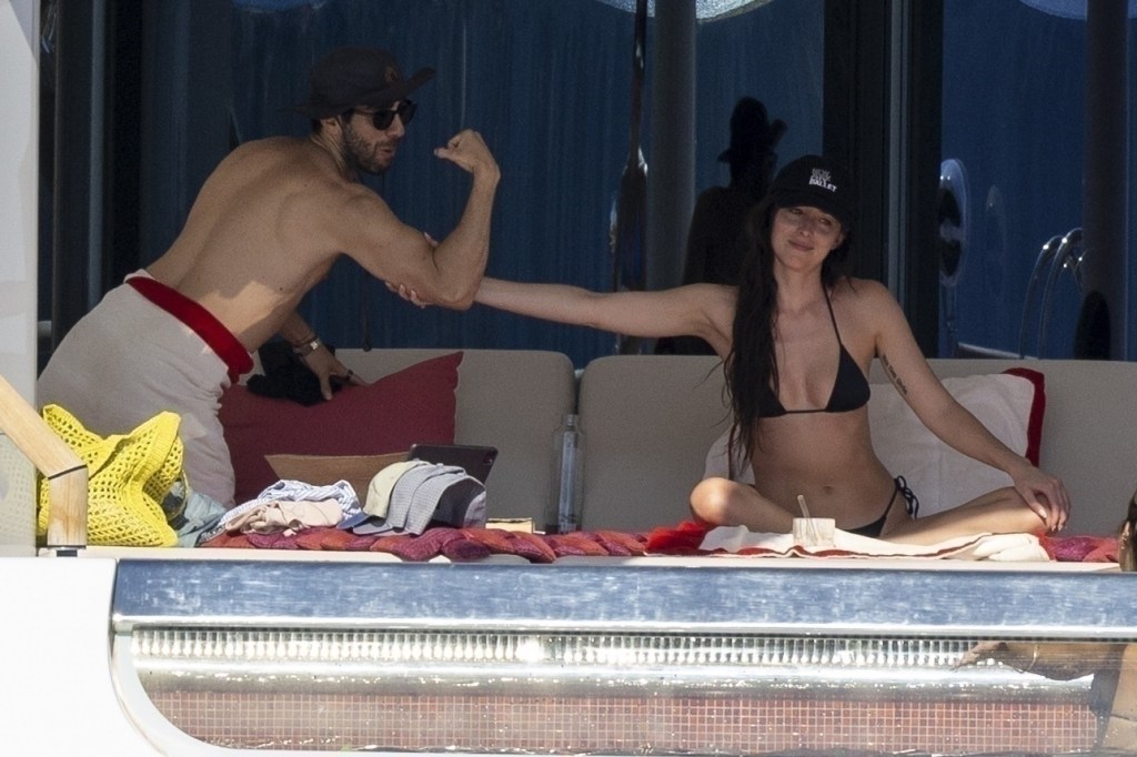 Dakota Johnson feeling a friend's bicep on a yacht in Ibiza, Spain