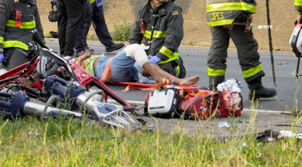 Emergency responders attending to an injured person at a multi-vehicle crash scene.